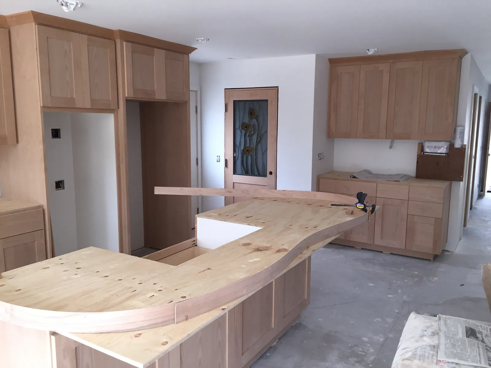 Unfinished kitchen during remodel with new wood cabinets and a plywood island countertop template.