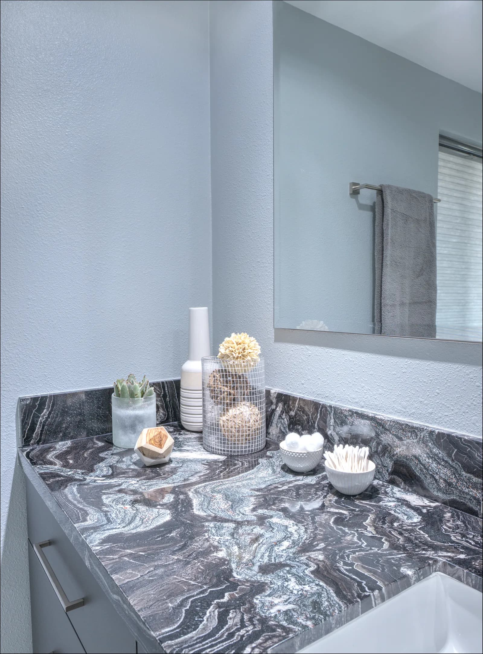 Close view of a bathroom vanity corner with dramatic black and white swirled granite and styled decor.