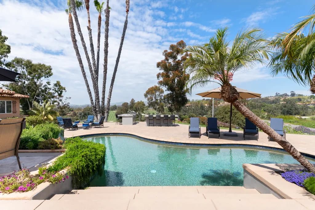 Backyard pool with palm trees at dusk.