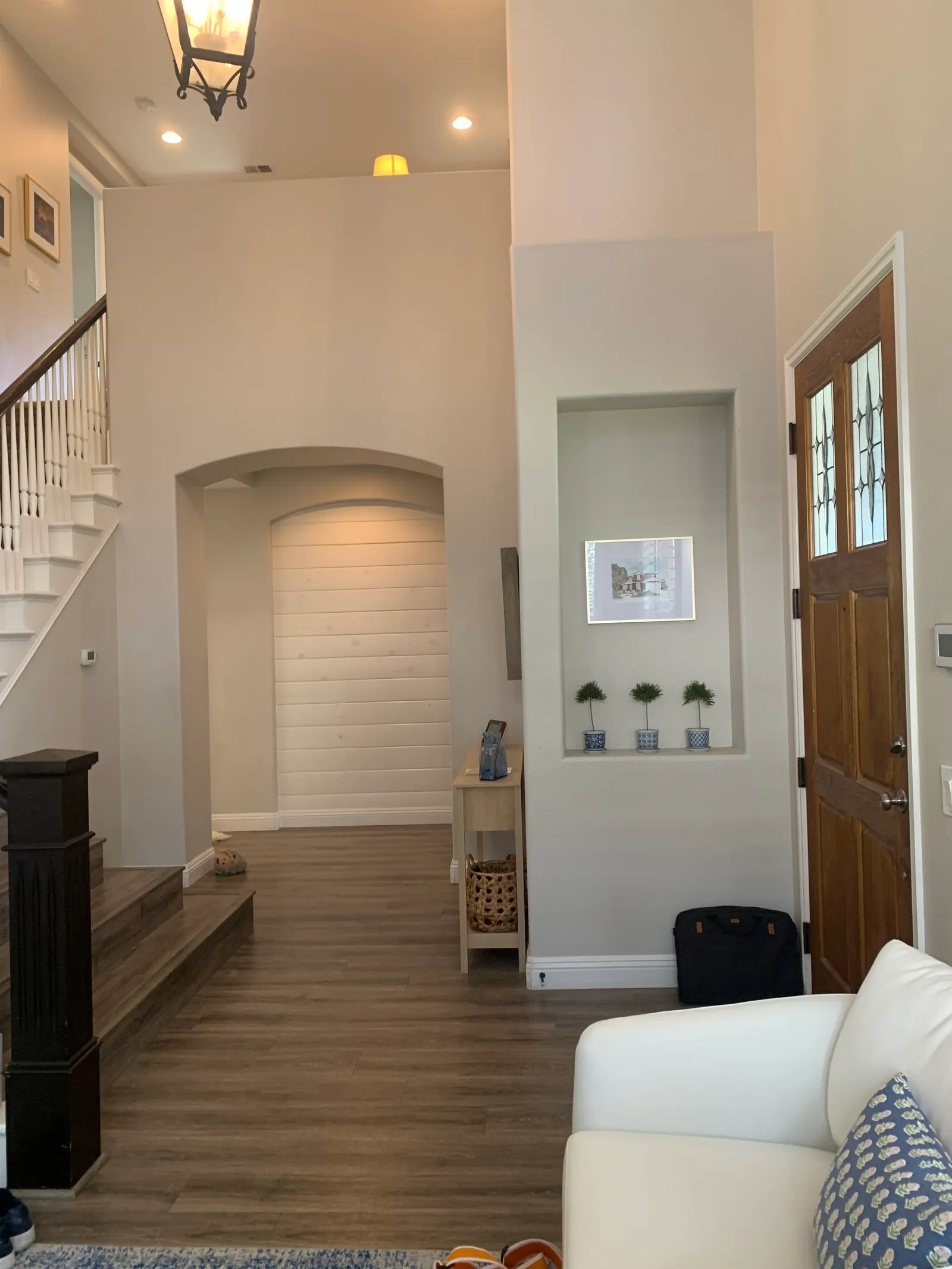 Two-story entry foyer with a white spindle staircase, wood treads, arched hallway, and decorative wall niche.