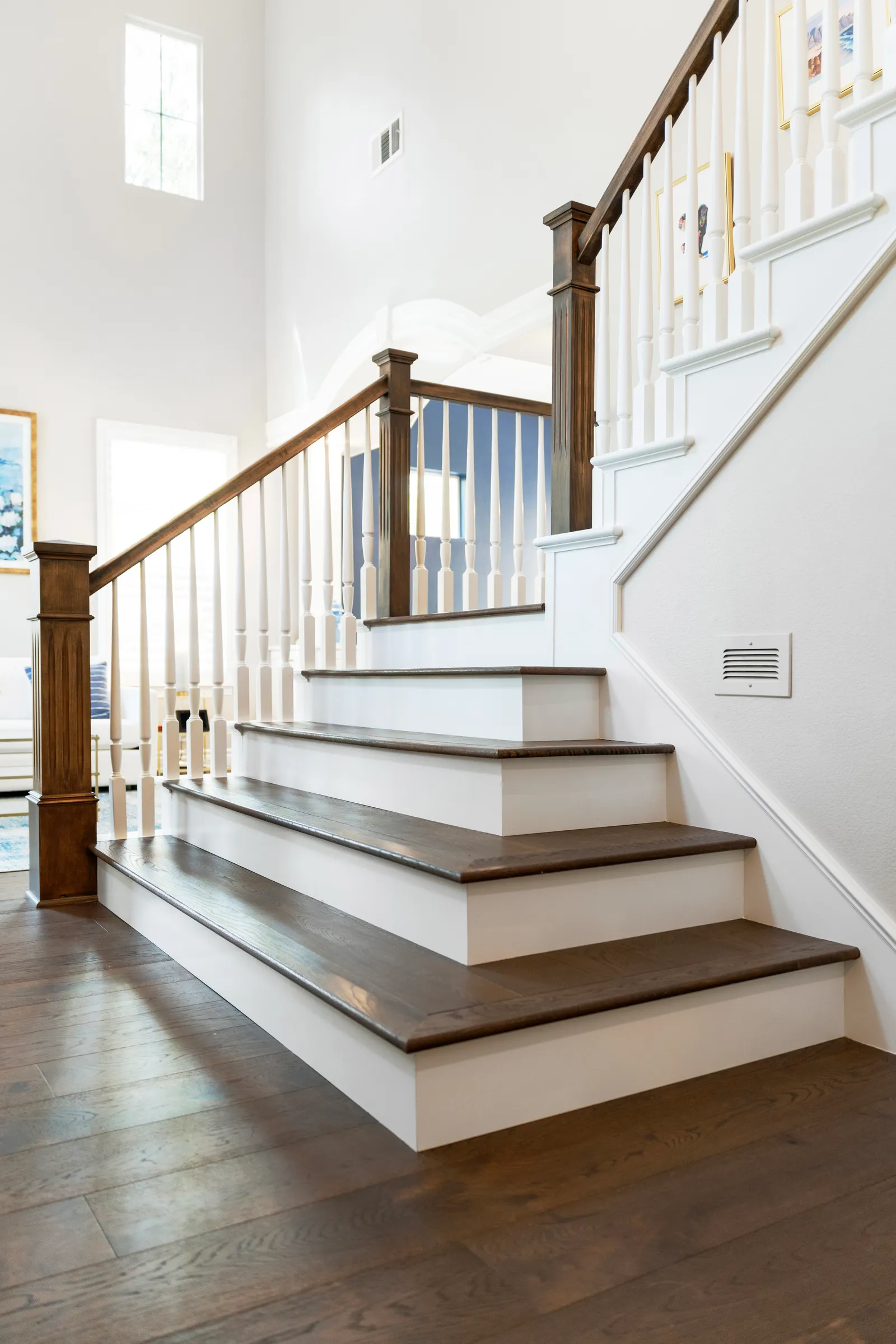 Bright two-story entry staircase with dark wood treads, white risers, and turned spindles.